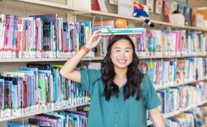 girl balancing books and apple on head