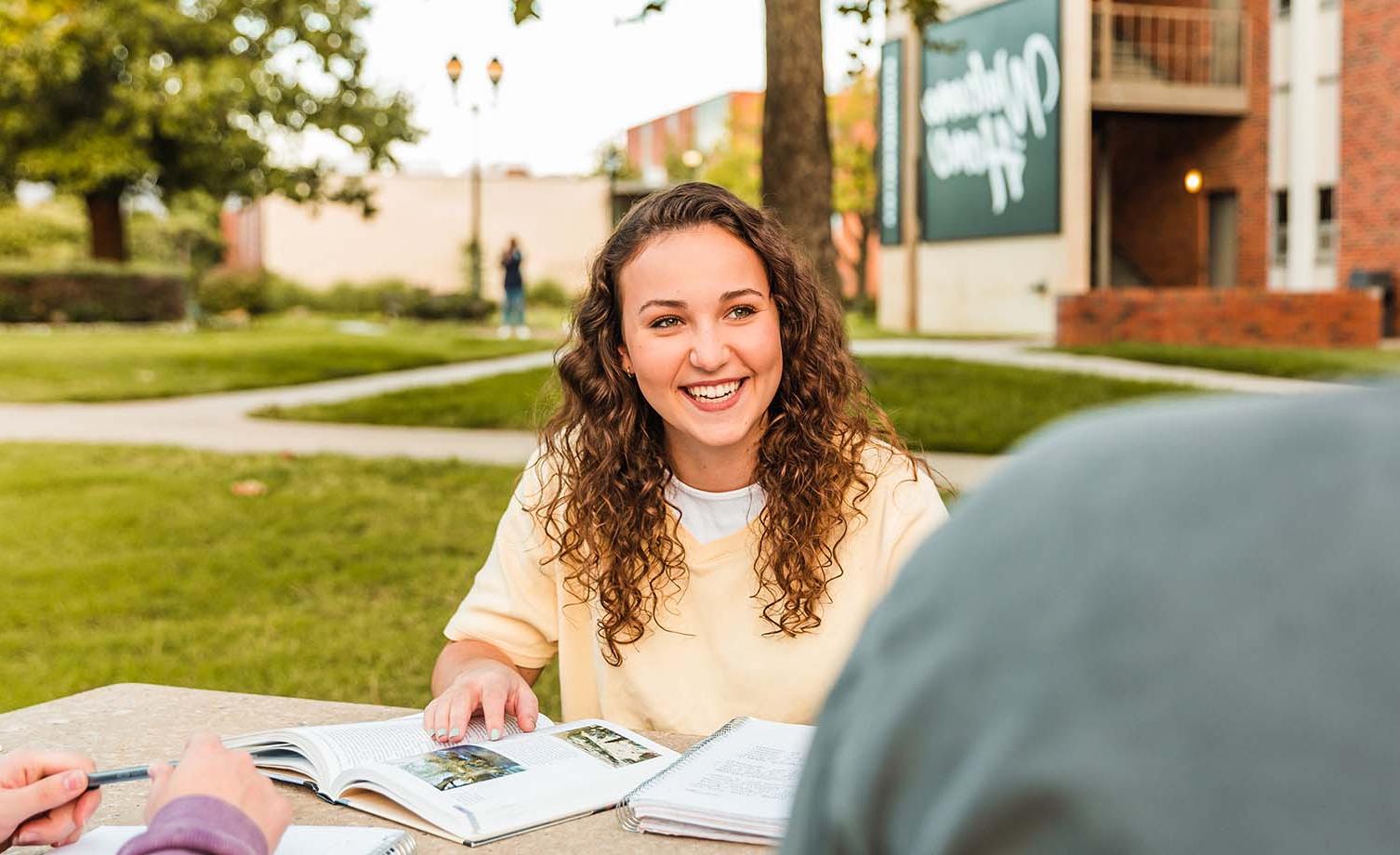 Girl sitting at picnic table working on homework